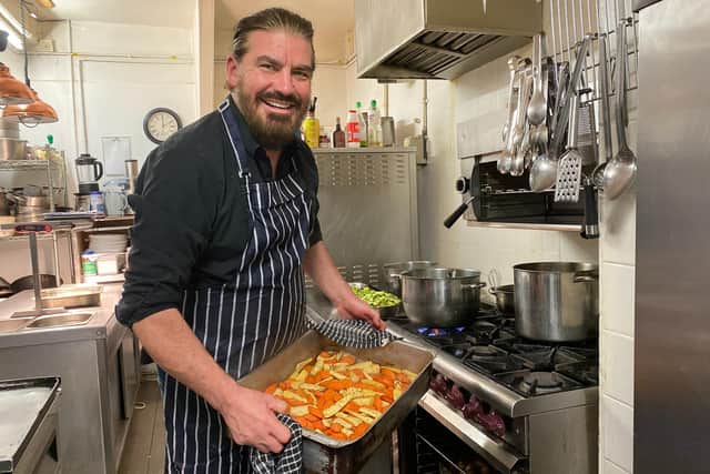 Paul Hugill MBE serving food in the kitchen.
