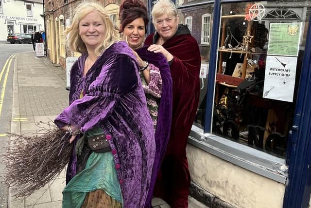Witches from left:  Shelley Mayes, Lynette Richardson and Sue Myland ride a broomstick outside their Flange & Prong shop.