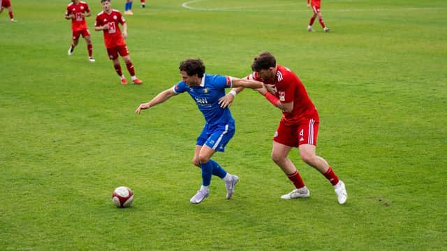 Declan Howe, Trinity's leading marksman holds off Ashton United's experienced Player/ Coach Sean Newton.