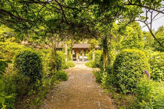 A rose-lined pergola leading to ...