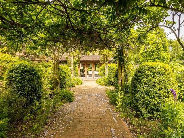 A rose-lined pergola leading to ...