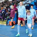 Mia Jackson walking out with Esme Morgan, defender for Women's Super League club Manchester City and the England women's national team.