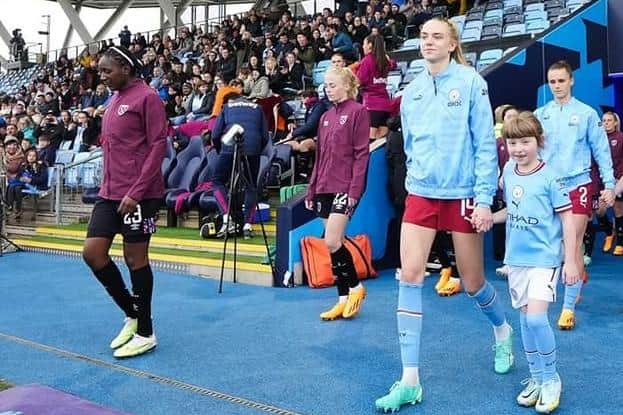 Mia Jackson walking out with Esme Morgan, defender for Women's Super League club Manchester City and the England women's national team.