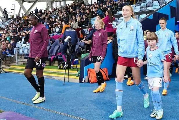 Mia Jackson walking out with Esme Morgan, defender for Women's Super League club Manchester City and the England women's national team.