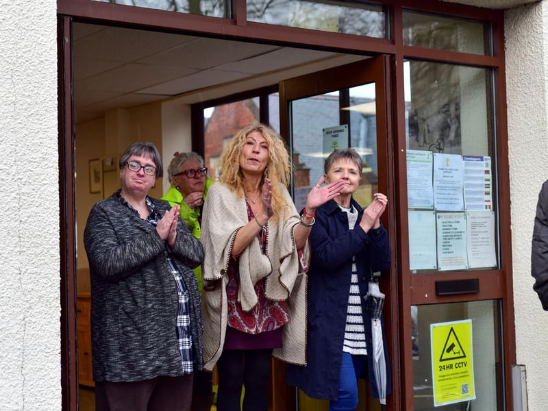 Shop workers stand outside to clap as the funeral procession passes by.