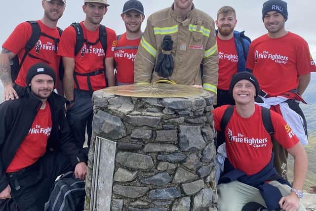 Jordan Powley reaches the top of Mount Snowdon in full kit, support by friends.