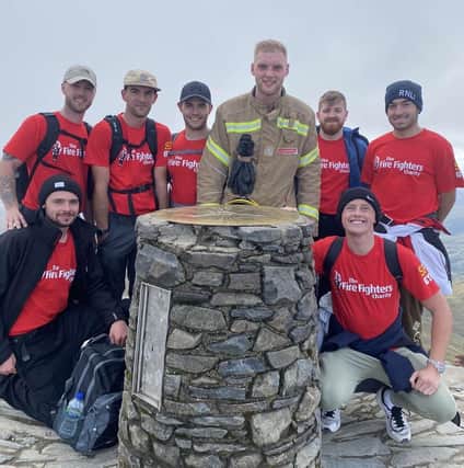 Jordan Powley reaches the top of Mount Snowdon in full kit, support by friends.