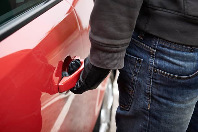 Car thief trying door handle to see if vehicle is unlocked