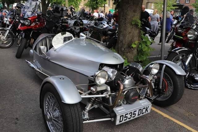 A gleaming vehicle lines up alongside the bikes.