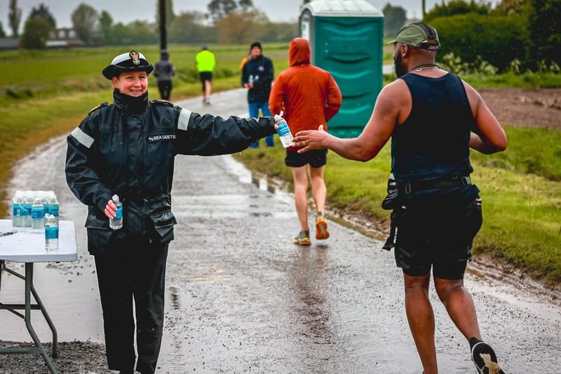 A volunteer marshal from the sea cadets hands out drinks to runners.