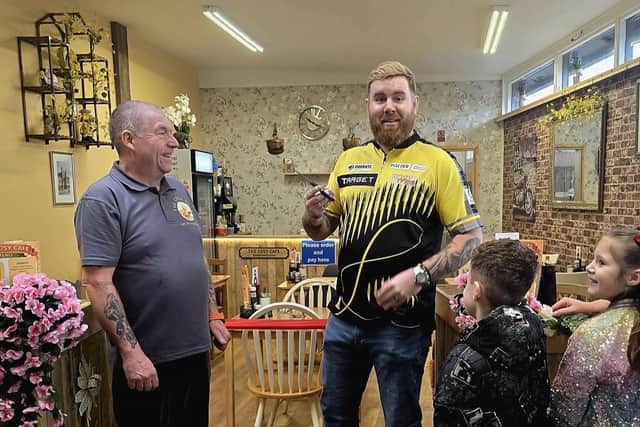 Professional darts player Scott Williams cutting the ribbon on The Cosy Cafe, Wrangle, alongside owner Anthony Knight.