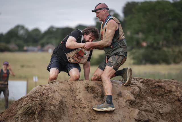 Ben helping a fellow competitor out of the Muddy Mega Mile obstacle.