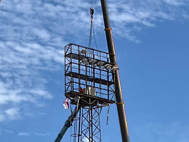 A crew member can just about be seen at the top of one of the floodlights.