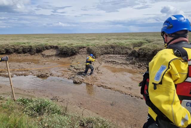 A Coastguard team member wades out through the mud to reach the casualty.