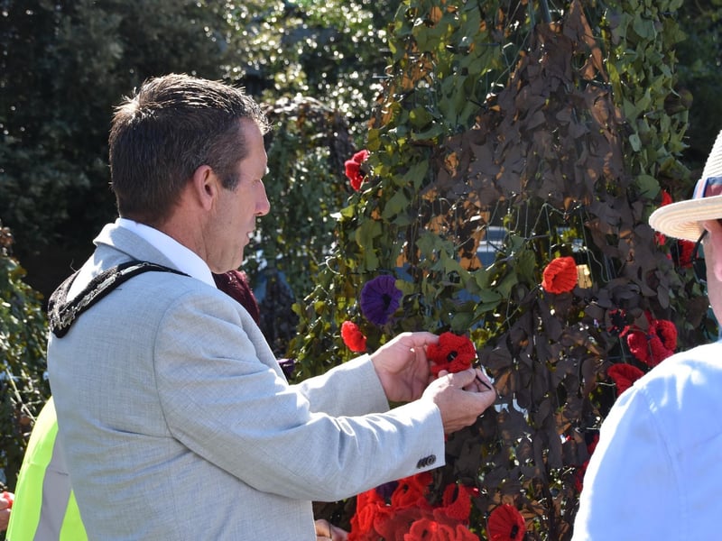 Mayor of Skegness Coun Adrian Findley busy tying on poppies for the Skegness RBL's 2025 poppy display.