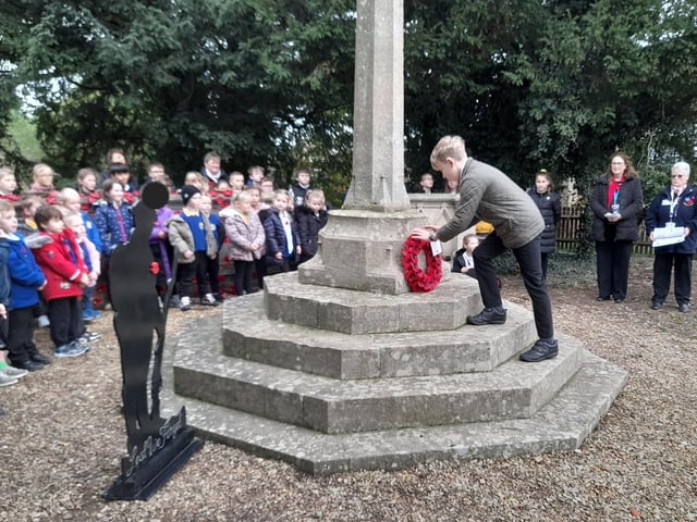 A Friskney All Saint Primary School pupil lays a poppy wreath at the village war memorial.