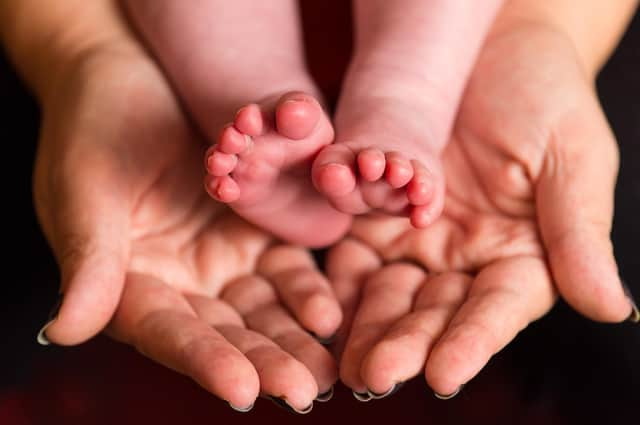 File photo dated 23/01/16 of a mother holding the feet of a new baby. More than half of single mothers do not automatically qualify to be enrolled in a workplace pension, a study has found.