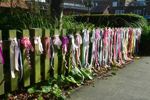The fence on the other side, adorned with colourful ribbons and bows.