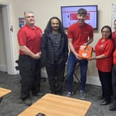 Josh Ellingworth of Defibshop (centre) - donating the defibrillator to Emma Heaysman, SAR-L volunteer to the right of the defibrillator, and team members.