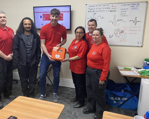 Josh Ellingworth of Defibshop (centre) - donating the defibrillator to Emma Heaysman, SAR-L volunteer to the right of the defibrillator, and team members.