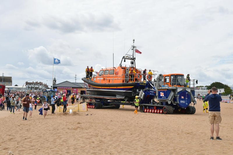 Crowds on the beach follow the lifeboat to the water.