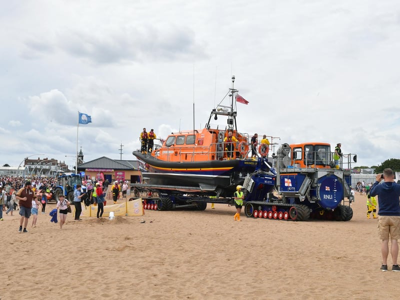 Crowds on the beach follow the lifeboat to the water.