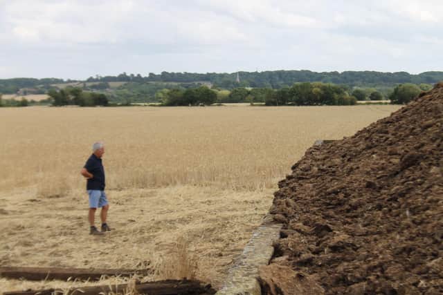 Andrew next to the heap with crops in the background showing how far the fire could have spread