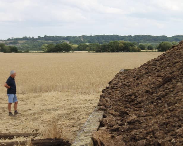 Andrew next to the heap with crops in the background showing how far the fire could have spread