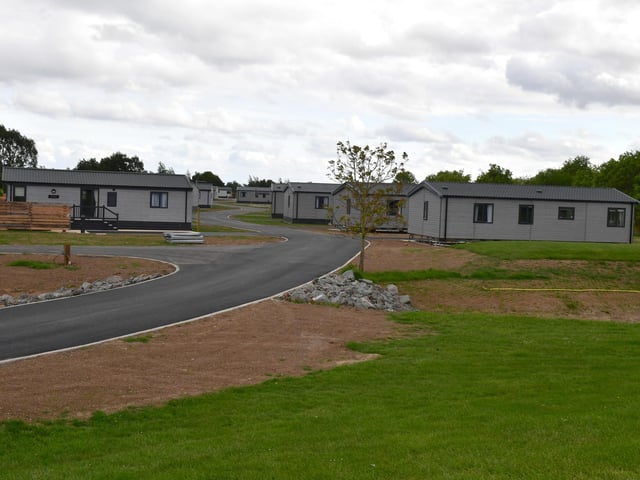 The luxury lodges sit along a winding road with views across the golf course.