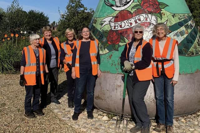 Some of the winning Boston in Bloom team celebrating their success by digging up weeds around the buoy in Central Park.
