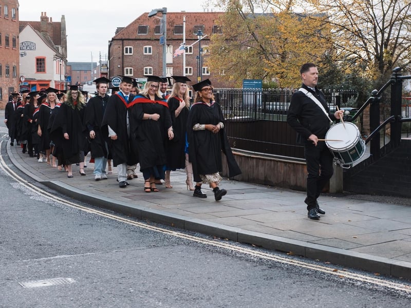 Graduates making their way through town, led by a drummer, for the ceremony.