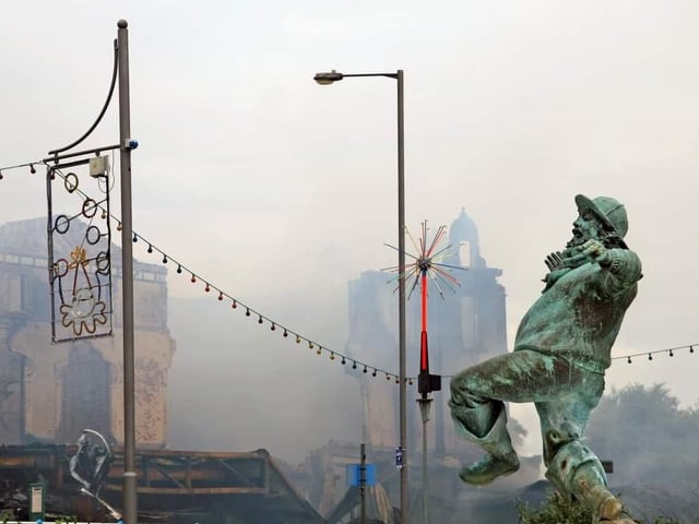 The Jolly Fisherman appears to gaze through charred illuminations  at the  haunting scene that was left after the fire.