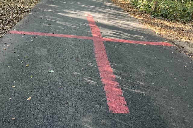 A Cross of St George symbol has appeared on the newly-restored road through the woods in Woodhall Spa.