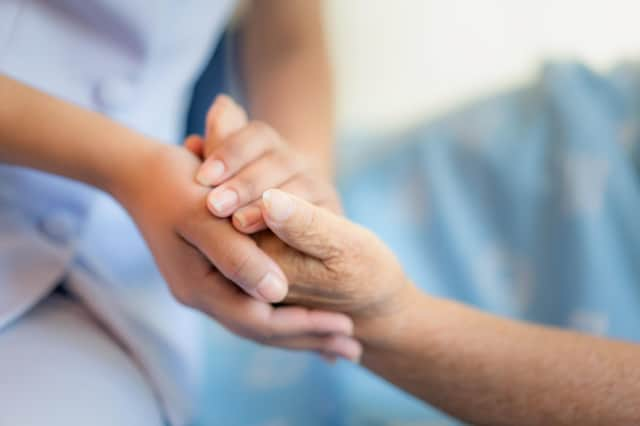 Nurse sitting on a hospital bed next to an older woman