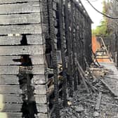 The fire damage to one of the resident's large sheds and fence, with the burnt row of conifers lining the ditch to the right of the image.