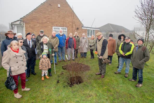 Mr Toby Dennis, Lord Lieutenant of Lincolnshire (centre) plants the tree in Bardney with residents looking on.