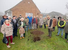 Mr Toby Dennis, Lord Lieutenant of Lincolnshire (centre) plants the tree in Bardney with residents looking on.