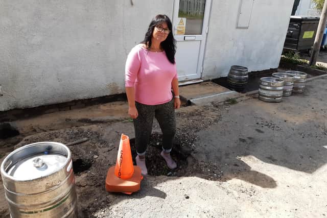 Club secretary Eve Bennett in one of the holes created by the rush of water onto the area surrounding the club house