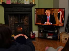 Members of a family listen as Britain's Prime Minister Boris Johnson makes a televised address to the nation from inside 10 Downing Street with the latest instructions to stay at home to help contain the Covid-19 pandemic (Photo: PAUL ELLIS/AFP via Getty Images)