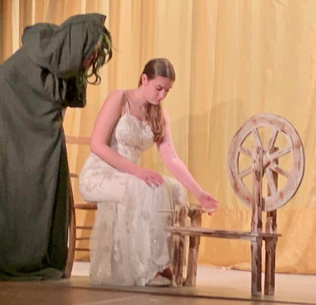 Sleeping Beauty and Bad Witch Hazel disguised as an old lady, coaxing her to spin some wool.