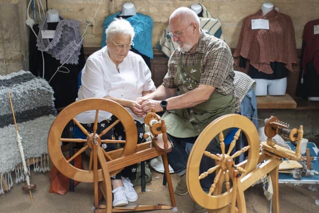 Colin Heggs provides a first lesson on his spare spinning wheel for Jacqui Cooper using Leicester longwool. Photo: Holly Parkinson