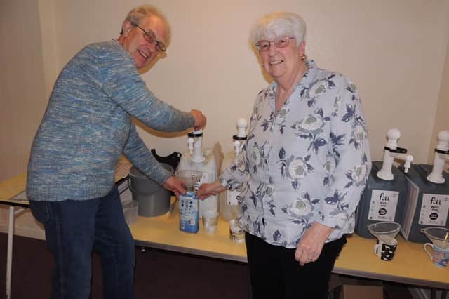 Coun Mervyn Head fills up parish councillor Maureen Corbett's bottles at the first day of their re-fill recycling project.