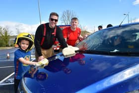 Firefighter Josh Hunt and Crew Manager Kel Brooks washing a car helped by Ezra Castro, aged five.