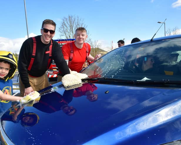 Firefighter Josh Hunt and Crew Manager Kel Brooks washing a car helped by Ezra Castro, aged five.