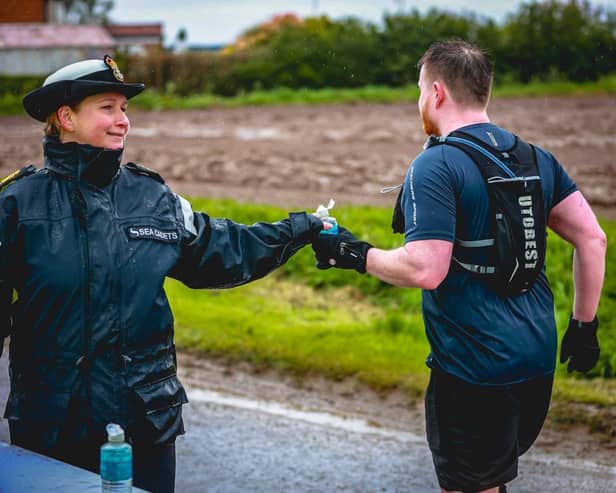 A volunteer marshal supports a runner at one of the drink stops.