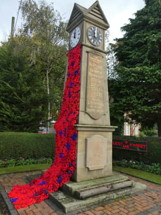 Stickford War Memorial Clock decorated with poppies for Remembrance Sunday.