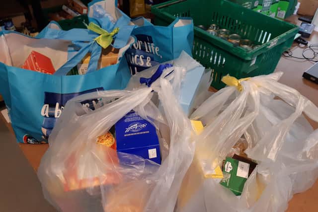 Food parcels for a single person (yellow tag), a couple (blue tag), and a family (green tag).