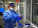 A nurse puts on PPE in a ward for Covid patients at King's College Hospital, in south east London. Picture date: Tuesday December 21, 2021.