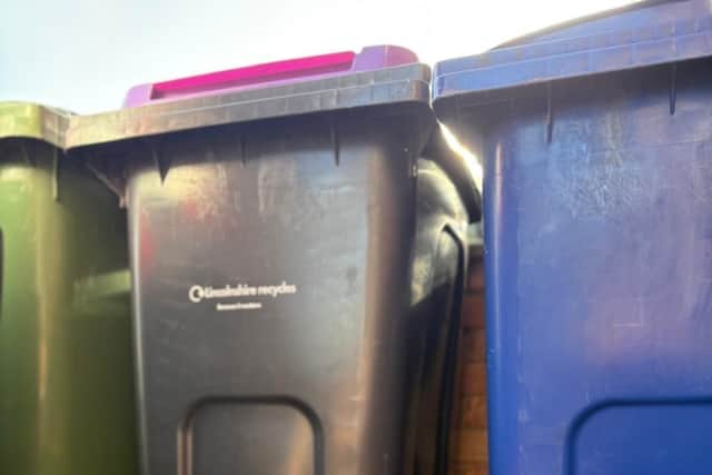 Outdoor food waste caddy pictured alongside standard wheeled bins in Boston Borough for size comparison. The compact design makes it easy to store while supporting food waste recycling.