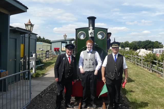 Matthew stands in front of vintage steam loco Jurassic with left, platform assistant Chris Bates and right, station master Calvin Roberts. Driver Jim Smith looks on from the loco's cab.